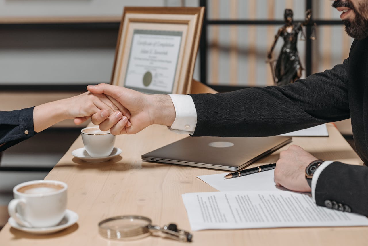 Home A formal handshake over a business contract in a corporate office setting.